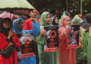Massa aksi memegang poster bertuliskan tuntutan aksi.